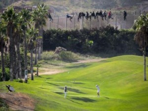 Inmigrantes saltan la valla mientras otras personas juegan al golf